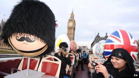 Giant decorated eggs driven past the Houses of Parliament, in central London, on an open-top tour bus