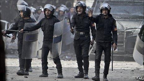 Line of riot police with shields, helmets and truncheons