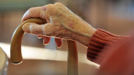 An elderly person's hand holding a walking stick