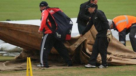 Ground staff cover the pitch at Queens Park