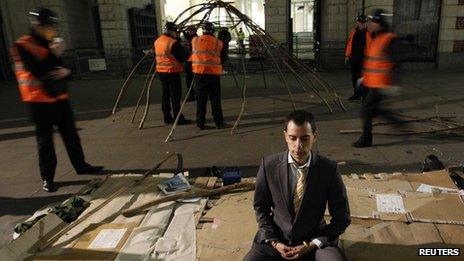 A protester meditating while bailiffs dismantle a tent