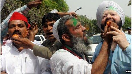 Samajwadi Party (SP) workers feed each other sweets to celebrate their victory at the party office in New Delhi on March 6, 2012