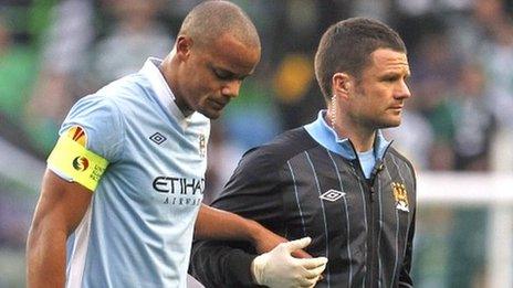 Kompany (left) is helped from the pitch after injuring himself in Portugal