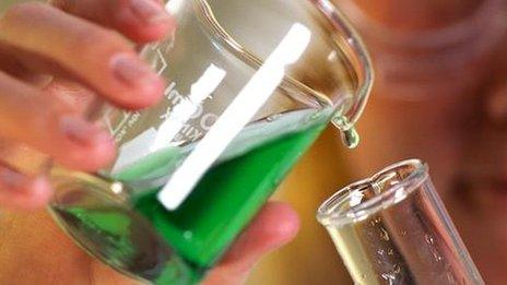 Laboratory technician pouring liquid from beaker into glass tube