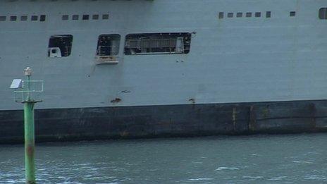 HMS Illustrious sailing into Portsmouth, with two small holes visible on its hull