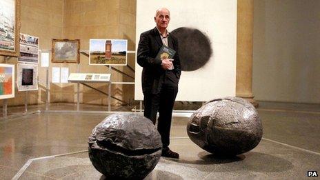 Patrick Keiller stands amongst works from the Robinson Institute Collection, an exhibition that considers the current economic crisis, at the Tate Britain