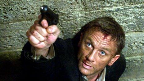 Daniel Craig aiming a gun in character as the fictional spy James Bond