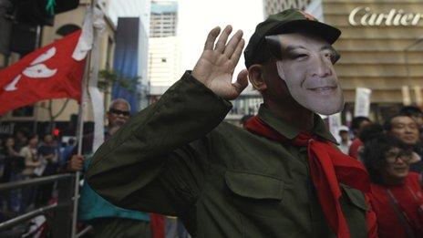 Protester wears a mask depicting CY Leung at a demonstration in Hong Kong on 1 April 2012