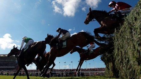 Horses jump a fence at Aintree