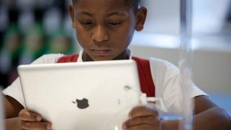 A young boy looks at an Apple iPad