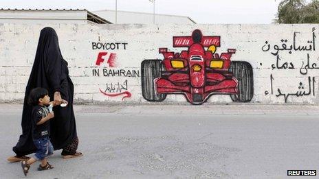 A woman and boy walk past graffiti urging the boycott of the 2012 Bahrain Grand Prix (18 April 2012)