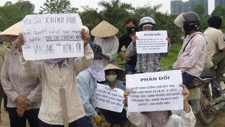 Farmers hold signs during a protest to protect their paddy fields from being part of a land grab to make way for the construction of a luxury Ecopark resort in Van Giang district, in Vietnam's northern Hung Yen province, outside Hanoi April 20, 2012