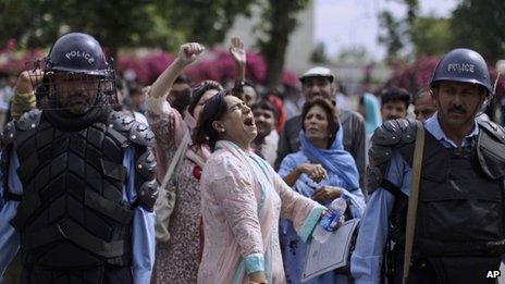 Pakistani riot policemen stand guard, as a supporter of Prime Minister Yousuf Raza Gilani, centre, shouts slogans in Gilani"s support