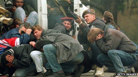 A Bosnian special forces soldier returns fire 6 April 1992 in Sarajevo as he and civilians come under fire from Serbian snipers
