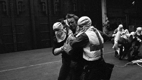 A survivor from the HMS Sheffield missile attack in 1982 is led away for treatment