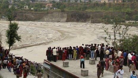 People in Nepal's Kaski district watch the flooded Seti River (5 May)