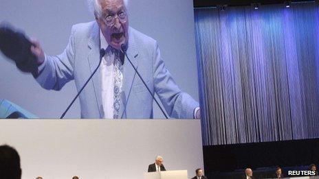 An unidentified shareholder is seen on a huge screen as he holds up his shoe while Swiss bank Credit Suisse