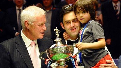 Barry Hearn looks on as Ronnie O'Sullivan celebrates winning the World Snooker Championship trophy with his son Ronnie Jr