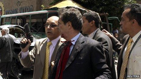 Fernando Londono, who is injured, walks as he is guarded by a bodyguard after an explosion in a central avenue in Bogota 15 May, 2012