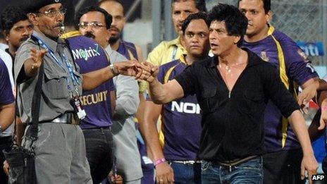 Bollywood actor and Shah Rukh Khan (R) gestures towards a security guard blowing a whistle to direct children accompanying him off the playing field on Wed 16 May night