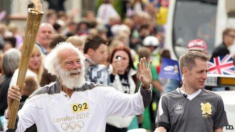 1948 Olympian Michael Lapage waves to the crowd as he takes his turn with the torch