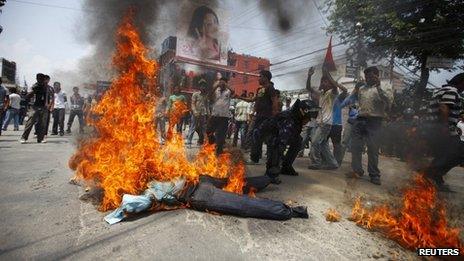 A Nepalese riot police officer drags away the burning effigy of Nepalese Prime Minister Baburam Bhattarai after it was set on fire by students affiliated to the Nepal Student Union, a student wing of the Nepali Congress Party, during a protest demanding the immediate resignation of the Prime minister in Kathmandu May 28, 2012.