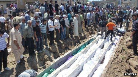 People gather for a mass funeral of those killed in Friday's attacks in Houla