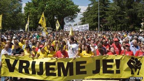 People hold a banner that reads "It's time" during a protest march in Podgorica