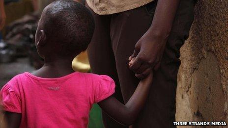 A child in Uganda holding an adult's hand