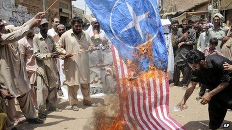 Pakistani protesters burn representations of US and NATO flags during a demonstration to condemn U.S. drone strikes in the tribal areas