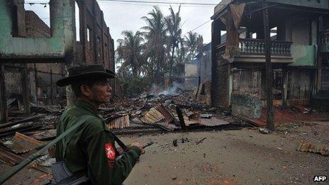A Burmese soldier patrols past destroyed houses in Sittwe June 14 2012