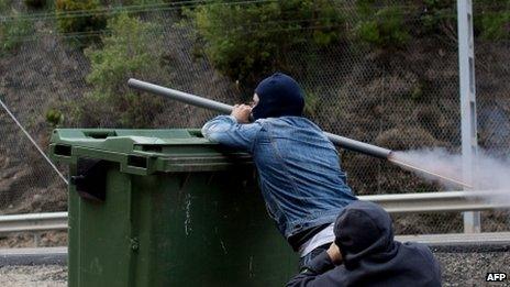 A Spanish miner on strike fires a homemade rocket-launcher over a wheelie bin in the northern Spanish town of Cinera