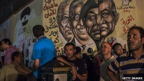 Egyptian men look on at graffiti of ousted Egyptian President Hosni Mubarak