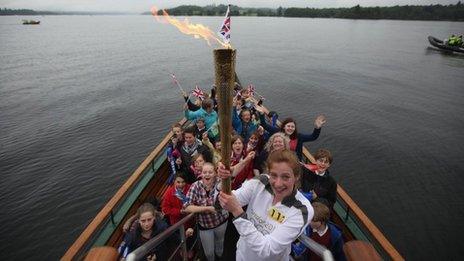 Triathlete Stephanie Booth, 15, with the Olympic flame and school children on board the Tern steam boat on Windermere, 21 June 2012