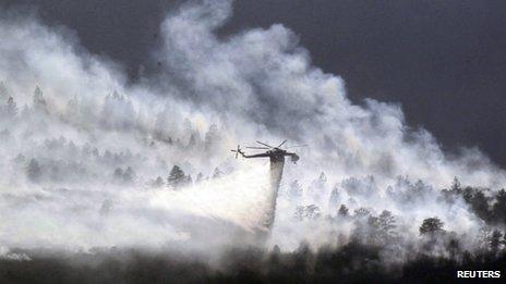 A helicopter drops water on the Waldo Canyon fire burning behind the US Air Force Academy, west of Colorado Springs, 27 June 2012