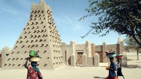 Women walk in front of Timbuktu's Djingareyber Mosque