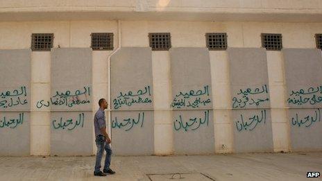 A Libyan man in September 2011 walks past the names of some of those who died at the Abu Salim prison in central Tripoli