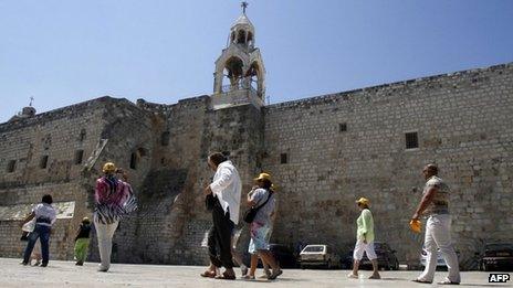 Tourists walk past the Church of the Nativity in Bethlehem