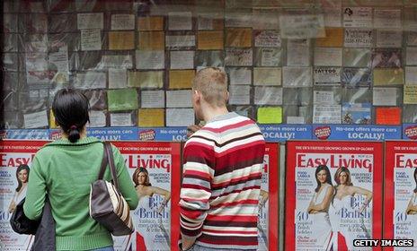 People looking at shop window displaying adverts