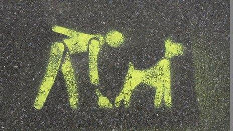 A stencil on the pavement asking you to clean up after your dog