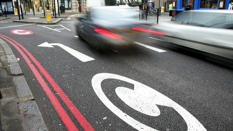 Cars drive pass congestion charge signs