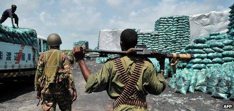 Militia allied with the government of Somalia and Kenyan soldiers walk through a charcoal loading area in Burgabo, southern Somalia on 14 December 2011