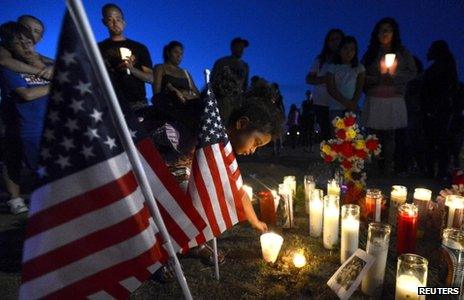 A girl places a candle by an American flag during a vigil for those shot at a cinema in Aurora, Colorado (20 July 2012)