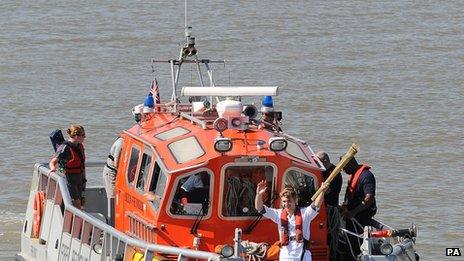 Aaron Reynolds carries the flame across the Thames in a London Fire Brigade boat