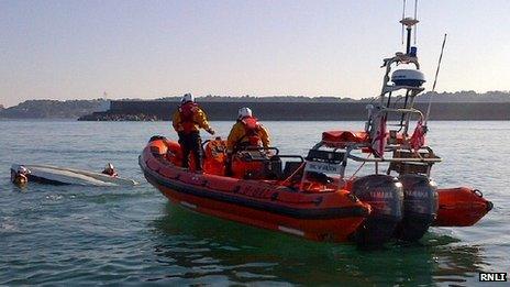 The RNLI helping an upturned sailing boat