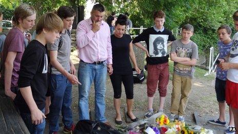 Jay Burgess, Carrie Valentine and teenagers look at floral tributes