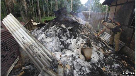 A policeman inspects destroyed paddy crop in a burnt house during violence near Goshaigaon town, in the northeastern Indian state of Assam July 25, 2012