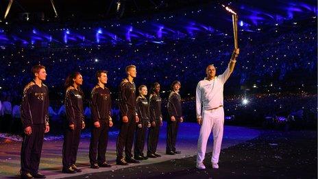 Sir Steve Redgrave carrying the torch along with seven young athletes given the honour of lighting the ceremonial flame