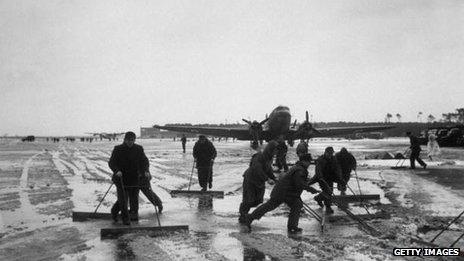 German workers clear snow throughout the night at an airfield, as the Berlin Airlift is temporarily delayed by the weather.