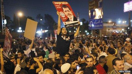 Supporters of Egypt's President Mohammed Morsi chant as they carry posters of him in front of the presidential palace in Cairo on Sunday